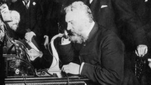 Black and white photo of Alexander Graham Bell using a phone