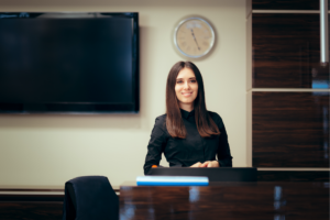 women wearing a black long sleeve top behind a hotel desk smiling at the camera