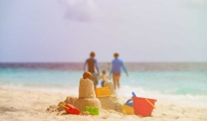 sand castle and toys on a beach with a family in the background