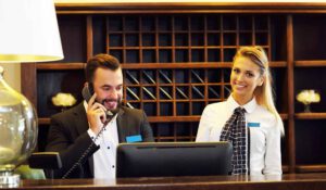 two hotel receptionists at desk, one on the phone