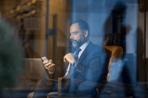 a man sitting and using his smartphone and laptop inside a hotel