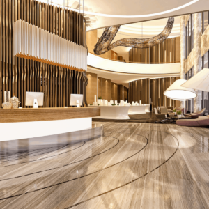 two story hotel lobby with large lighting, a stone wall, front desk with wood accents and two computer monitors, and a large hanging ceiling decoration. tones of brown, yellow, white, grey and gold