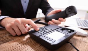person typing in phone number on a landline phone