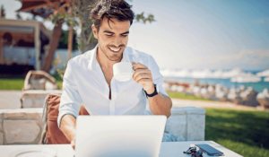 man drinking coffee outside while working on his computer