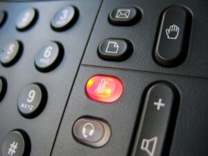 close up of a landline showing a red lit mute button
