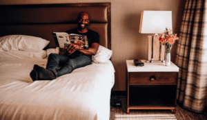 Man sitting on hotel bed reading magazine
