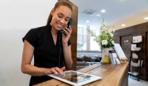 Female hotel receptionist on phone and tablet