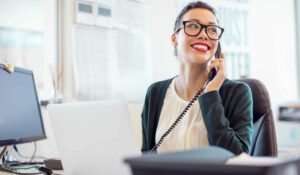 Hotel receptionist sitting at desk on phone while smiling