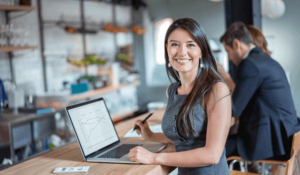 business women working on computer while looking at the camera smiling