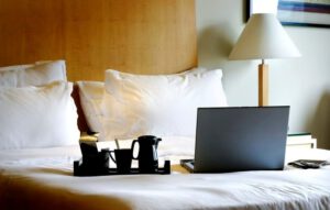 a gray laptop and black modern tea set sitting on a hotel bed