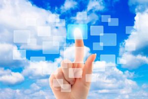a hand touching white squares floating in the air with a blue sky and clouds in the background
