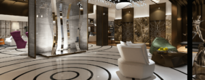 hotel lobby with a white floor that has a circular design, futuristic looking chairs, tabes, and sculpture. Large stone accent wall and crystal installation on the ceiling, whites, greys, brown accents