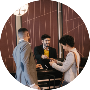 A man and a woman at the front desk of a hotel receiving a pamphlet from the man working at the hotel desk